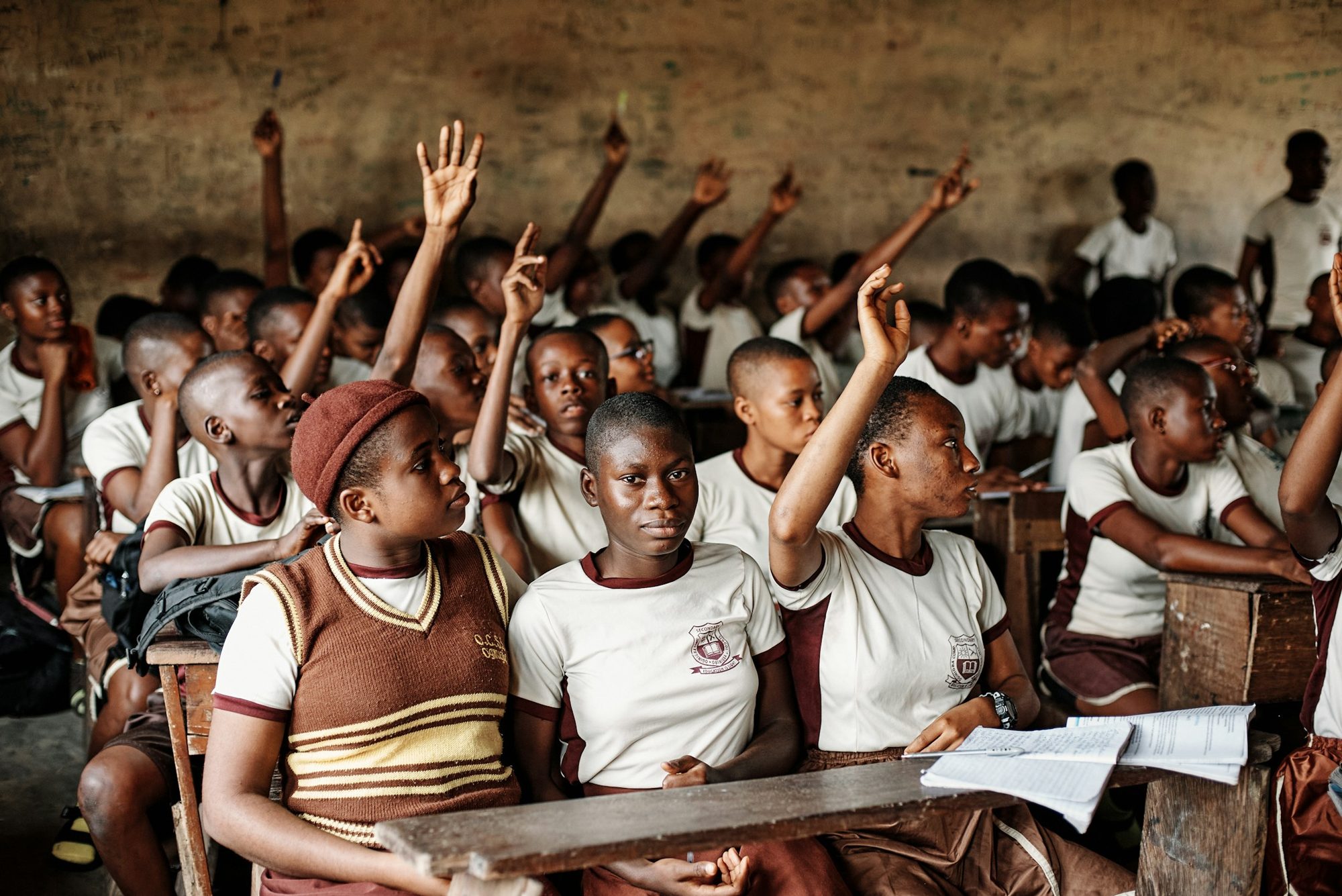 Pupils in a classroom raising their hands to answer a question