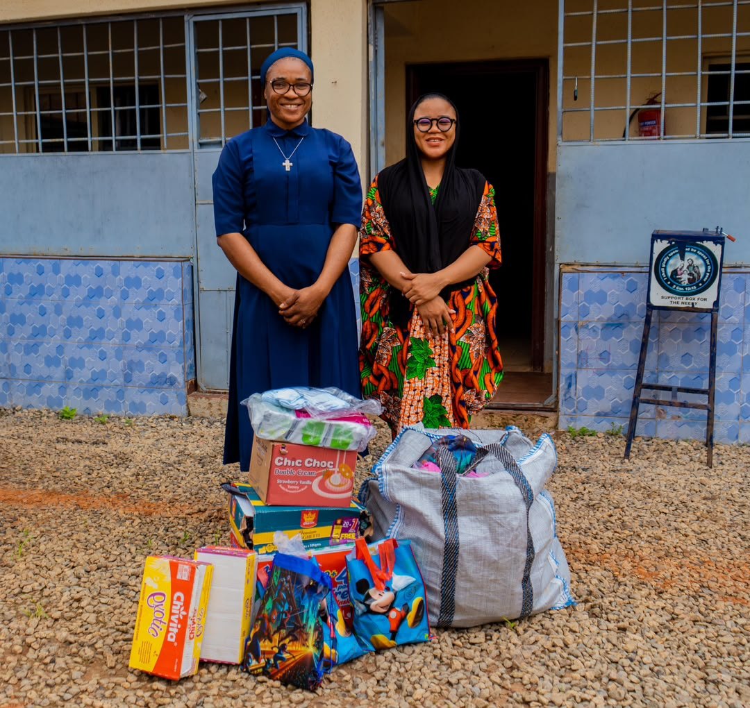 Anita Ejumudo and one of the Sisters standing outside the Home behind the donated supplies