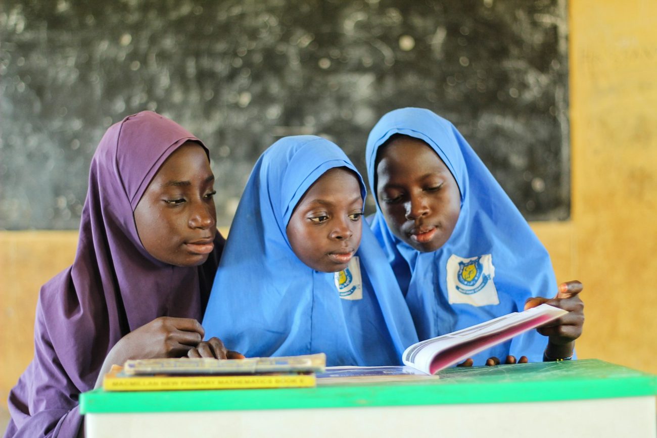 Three schoolgirls reading a textbook together